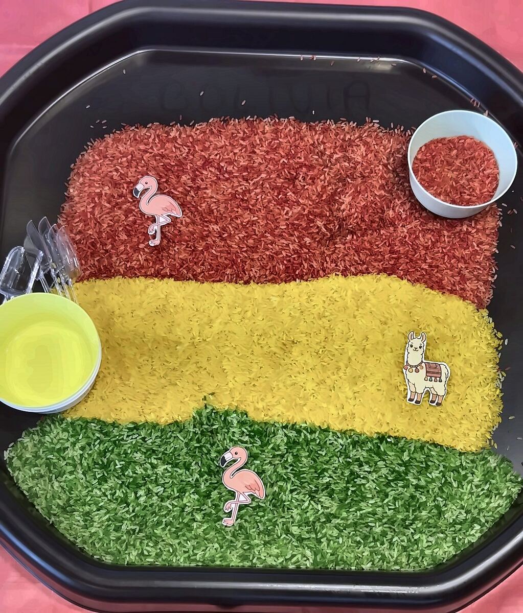 A sensory tray of red, yellow and green rice in the colours of the Bolivian flag