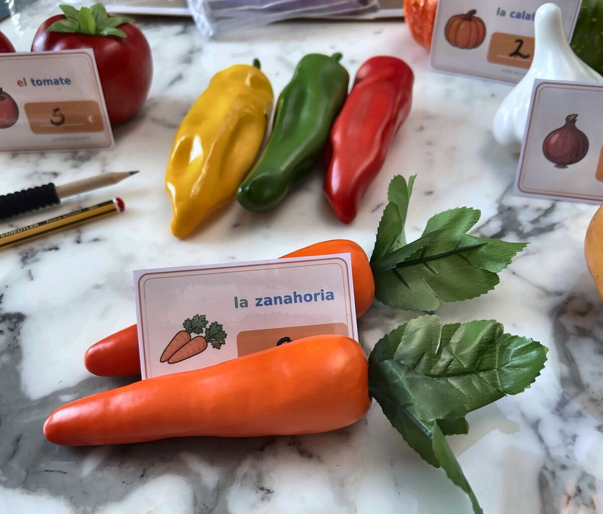 Toy vegetables laid out with Spanish price cards for a market game